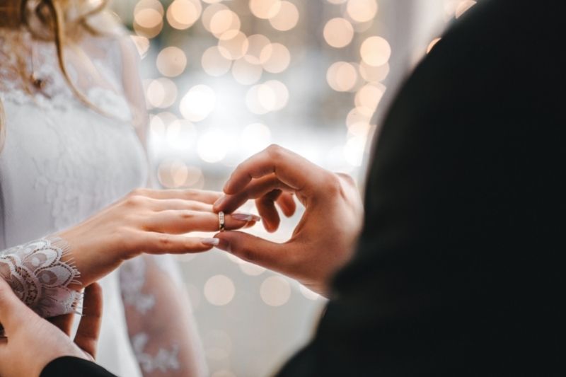 Man putting ring on wife's finger at wedding