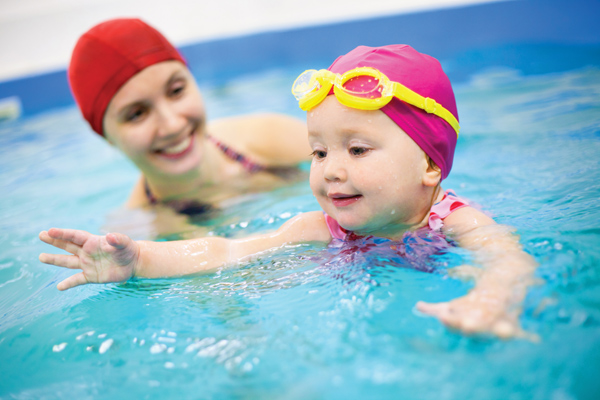 kid and teacher during swimming lesson for kids