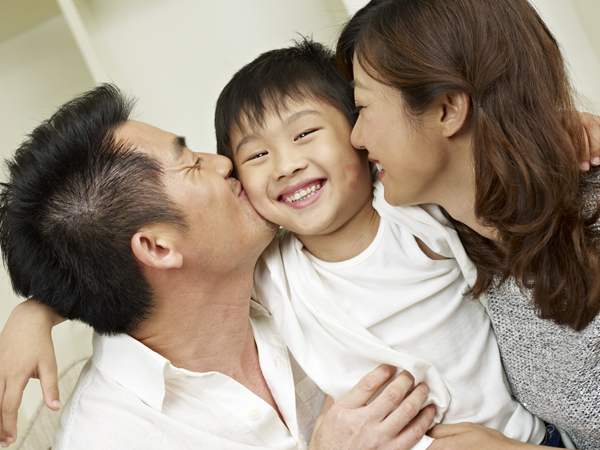 parents kissing a child's cheek