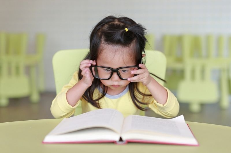 child struggling to read book because she needs vision therapy