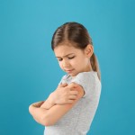 Little,Girl,Scratching,Arm,On,Color,Background.,Allergy,Symptoms