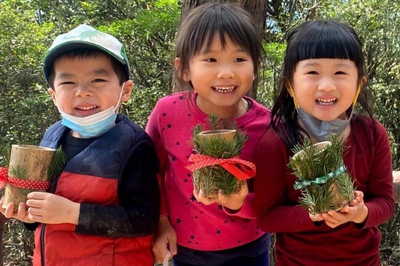 Asian small children holding art made from leaves 