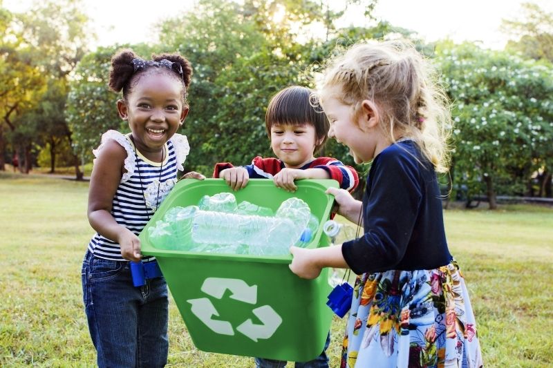 three children's holding a recycling bix