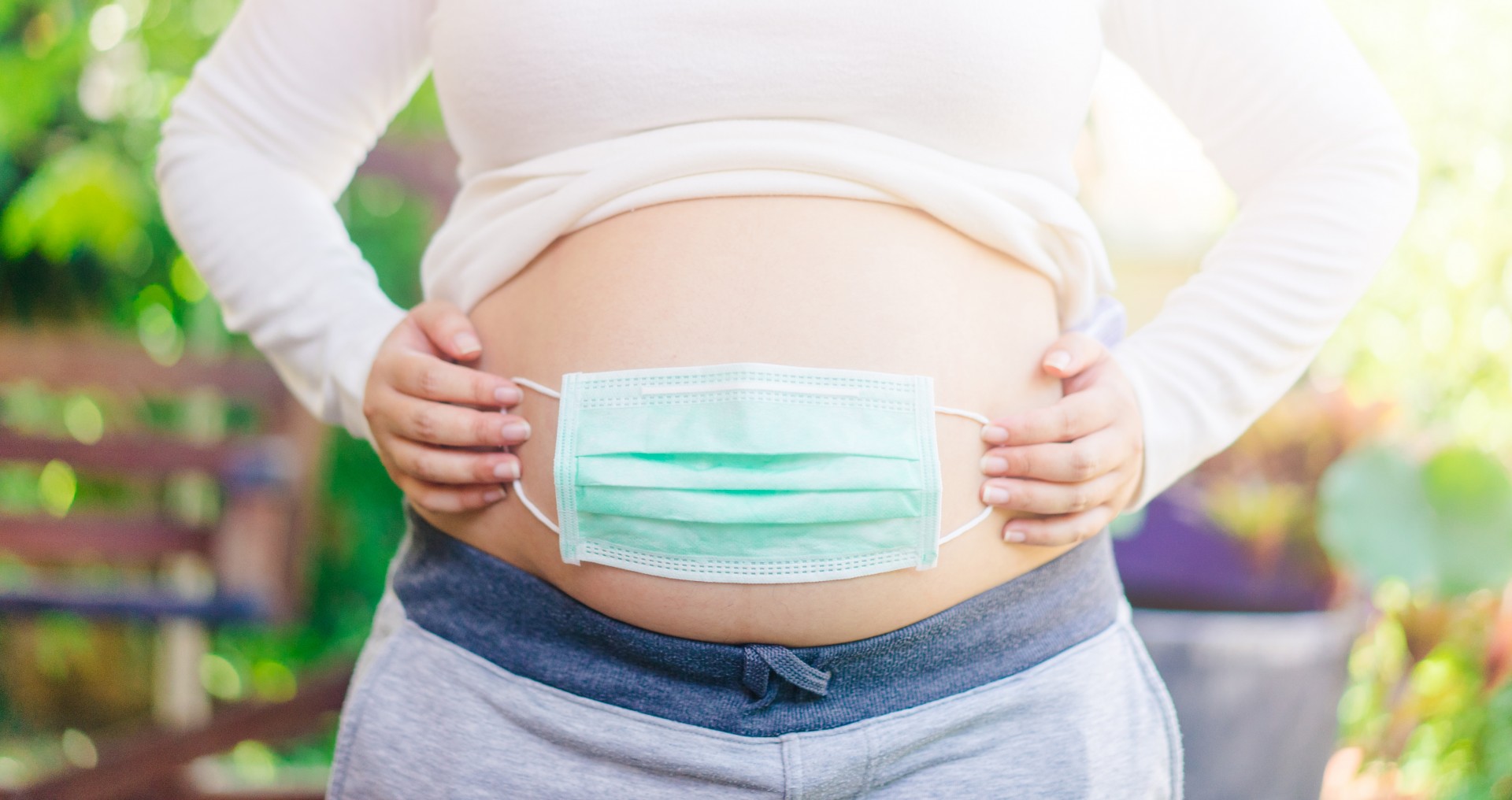 pregnant woman with mask on her stomach - Pregnancy and Childbirth During COVID