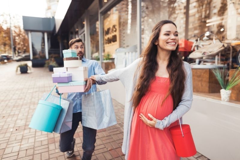 Pregnant woman shopping with husband carrying lots of bags