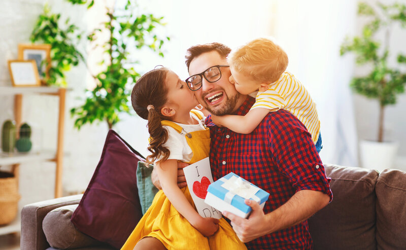 children giving their dad a kiss after giving them a christmas gift
