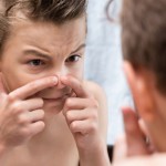Boy popping pimple