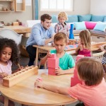 Teacher,And,Pupils,Working,At,Tables,In,Montessori,School