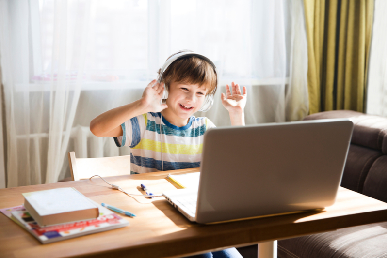 smiling young boy home learning on computer