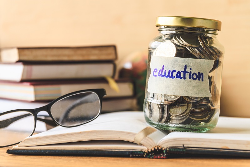 Books on a table and a jar of money with an education label on it