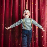Young,Boy,Dressed,As,Clown,Performing,On,Stage,With,Open