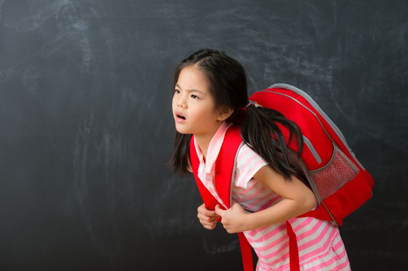 young girl holding a heavy backpack