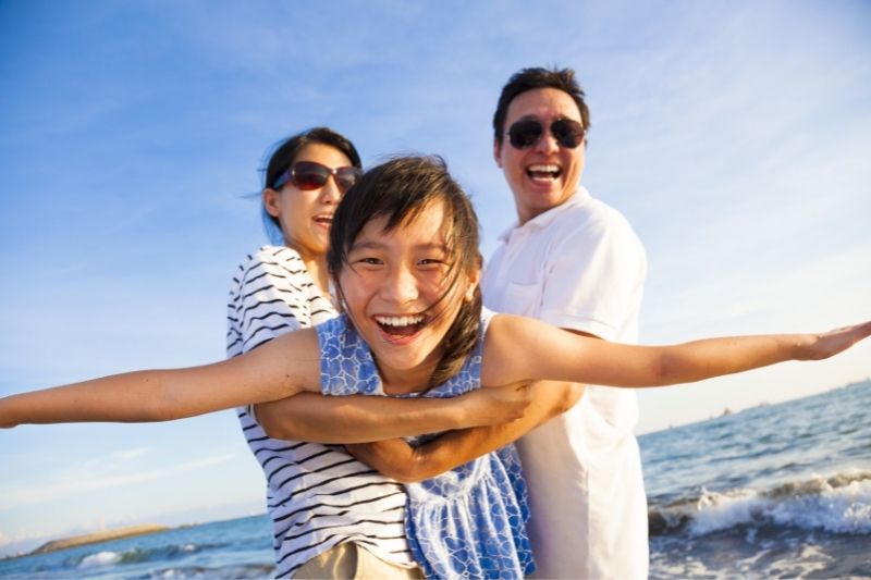 Ypung girl smiling being lifted up by her parents