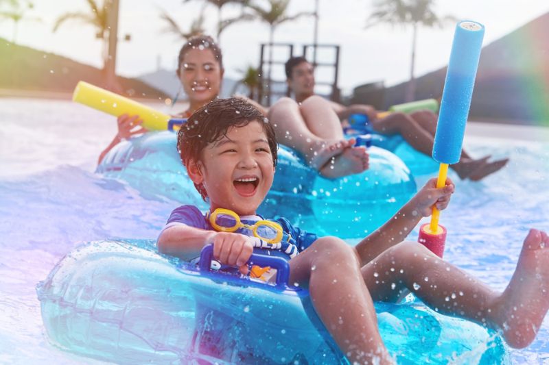 Family in a water park, sitting on tubes.